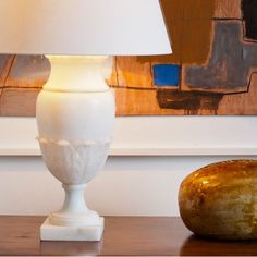 a white lamp sitting on top of a wooden table next to a loaf of bread