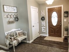 a white bench sitting in front of a wooden door next to a doorway with wreaths on it