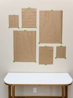 several pieces of brown paper taped to the wall above a white table with green tape on it