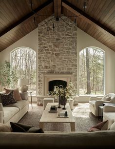 a living room filled with furniture and a fire place in front of two large windows