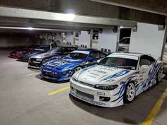 several cars parked in a parking garage with one car painted white and the other blue