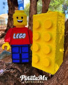 a lego man is standing next to a tree with his hand on the back of it