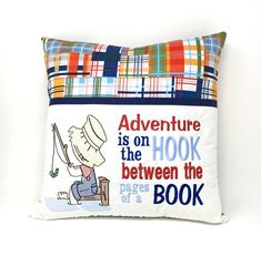 a pillow with an image of a boy holding a fishing pole and saying adventure is on the hook between the pages of a book