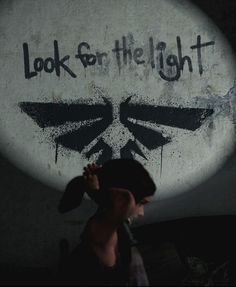 a man walking past a wall with graffiti on it's face and the words look on the light written in black