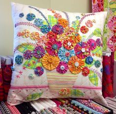 a colorful pillow with flowers on it sitting next to other pillows and ties in a store