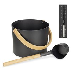 a black pot with wooden handle next to a thermometer on a white background