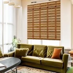 a living room filled with furniture and large windows covered in shades of brown bamboo blinds