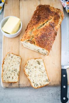 sliced loaf of bread sitting on top of a cutting board next to butter and knife