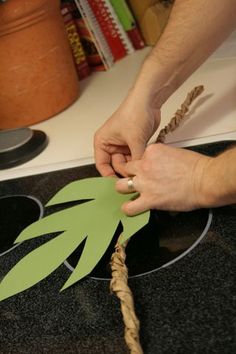 a person cutting out a paper palm tree with a pair of scissors and twine