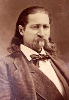 an old photo of a man with long hair and a beard wearing a suit jacket