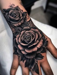 a woman's hand with black and white roses on it, in the middle of her arm