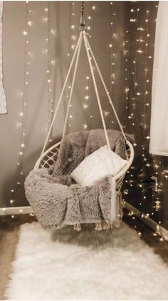 a hanging chair with some lights on the wall behind it and a rug in front of it