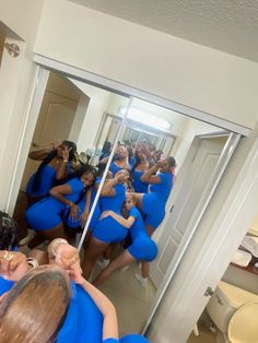 a group of women in blue dresses taking selfies with their cell phones while standing in front of a mirror