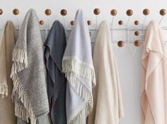 several different colored towels are hanging on a coat rack with wooden pegs in front of them