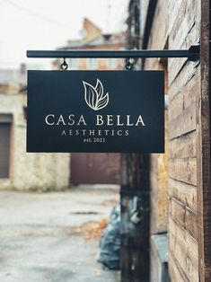 a black sign hanging from the side of a building that says cascabella aesthetics