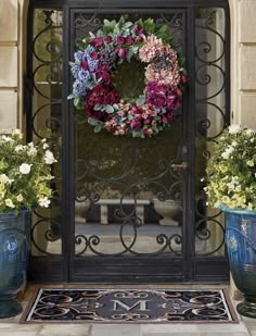 a door with a wreath on it and two blue vases next to it