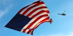 an american flag flying next to a helicopter