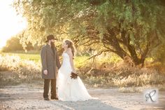 a bride and groom are standing in the dirt