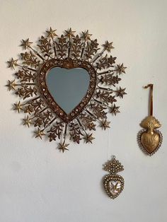 a heart shaped mirror sitting on top of a wall next to two other pieces of jewelry