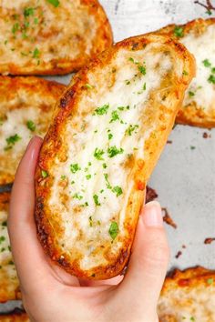 someone is holding up some bread with cheese and parmesan on it in their hand