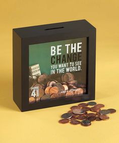 a black box with coins in front of it that says be the change you want to see in the world