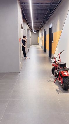 a man standing next to a red motorcycle in a hallway with yellow and white walls