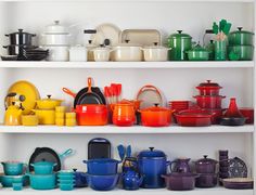 the shelves are filled with pots and pans on them in different colors, sizes and shapes