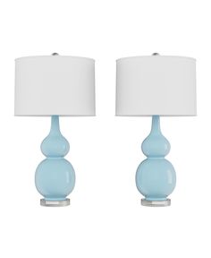 two blue glass table lamps with white shades on each lamp and one is turned off