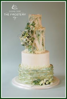 a three tiered cake with white flowers and greenery on top