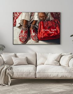 a living room with a white couch and red shoes on the floor, in front of a large painting