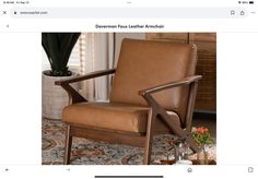 a brown leather chair sitting on top of a rug next to a potted plant