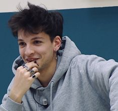 a young man sitting down with his hand on his chin and looking at the camera