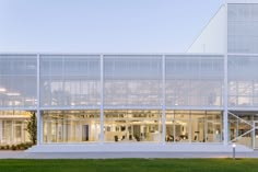 an office building with glass walls and large windows on the outside, surrounded by green grass