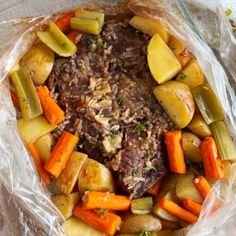 meat and vegetables wrapped in plastic wrap on top of a white tablecloth covered with foil