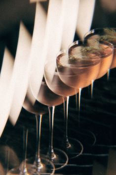 several glasses filled with different types of drinks on top of each other and lined up in rows