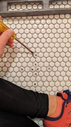 a person is sitting on the floor with an orange shoe polisher in their hand