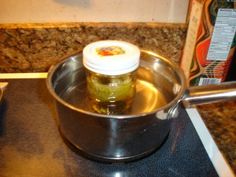 a sauce pot filled with pickles sitting on top of a stove