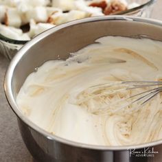 a metal bowl filled with white batter next to other bowls full of marshmallows