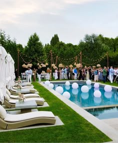 a group of people standing in front of a pool surrounded by lawn chairs and balloons