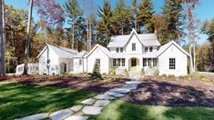 a white house surrounded by trees in the fall with stepping stones leading up to it