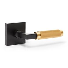 the black and gold toilet paper holder is mounted on a white wall with a square handle