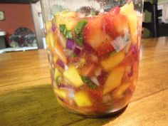 a mason jar filled with sliced fruit on top of a wooden table