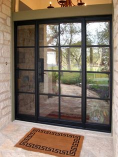 an open door leading to a patio with a rug on the floor and chandelier above it