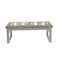 two stainless steel bowls sit on top of a wooden table with metal legs and feet