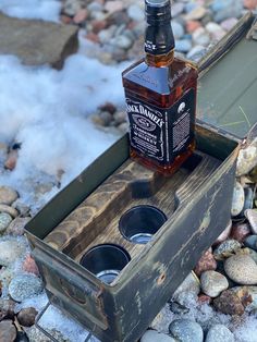 a bottle of jack daniels whiskey sitting in a wooden box on top of some rocks