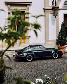 a black car parked in front of a building with potted plants on the side