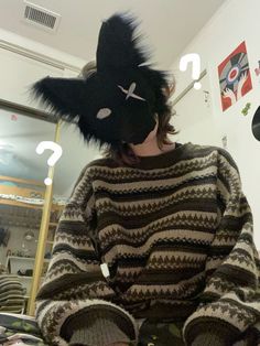 a woman wearing a black and white striped sweater with a cat mask on her head