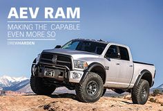 a silver truck driving on top of a rocky hill with mountains in the back ground