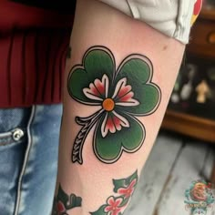 a woman's leg with a shamrock tattoo on it and flowers in the center