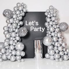 a black sign that says let's party with silver balls around it and an umbrella